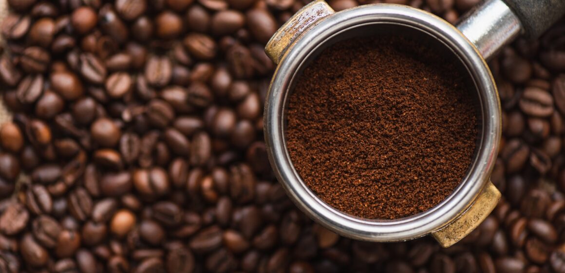 top view of ground coffee in portafilter on coffee beans background
