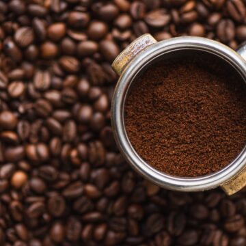 top view of ground coffee in portafilter on coffee beans background