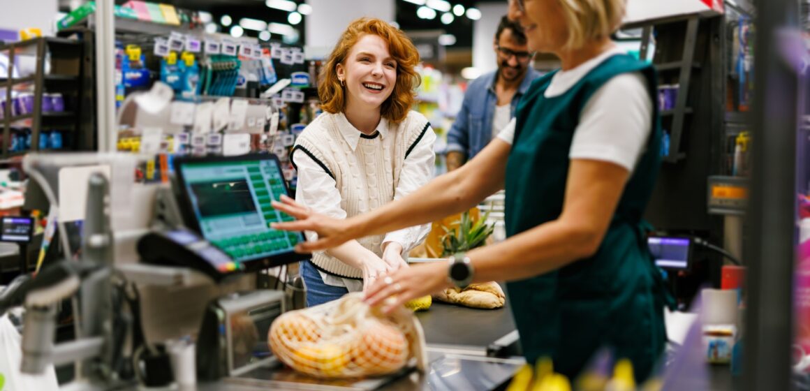 Cashier scanning groceries at supermarket checkout with customer paying for shopping