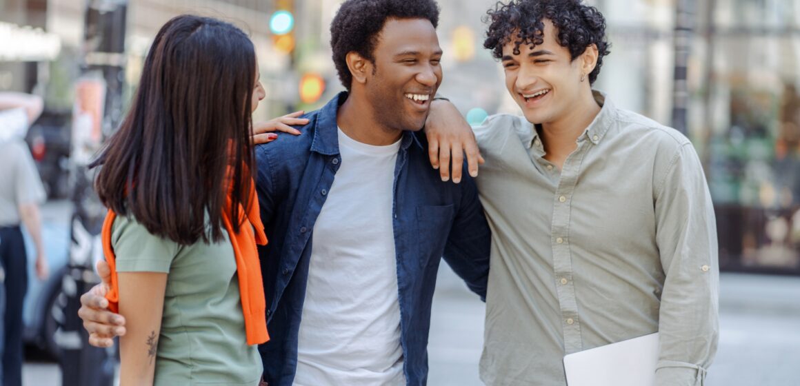 Multiracial young people talking on street near university campus smiling. Planning startup together