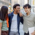 Multiracial young people talking on street near university campus smiling. Planning startup together