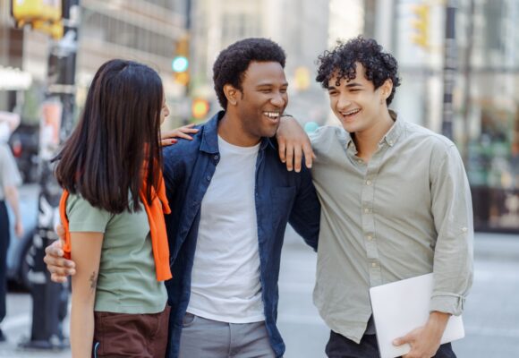 Multiracial young people talking on street near university campus smiling. Planning startup together